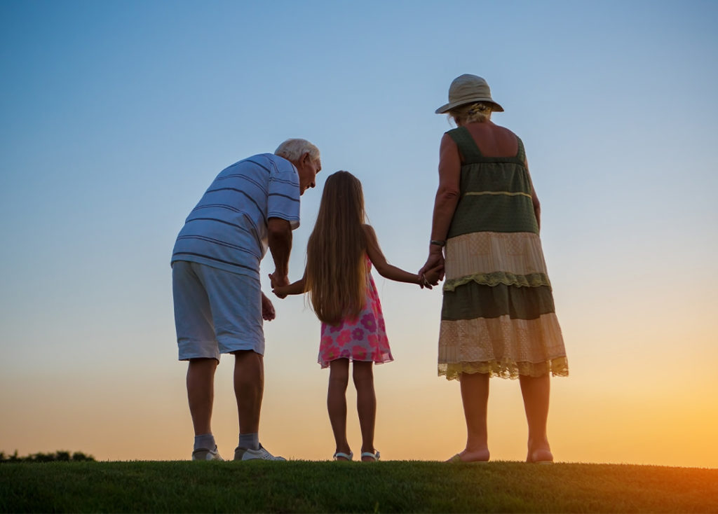 grandparents standing at the top of a hill watching sunset with their granddaughter money for retirement cedar rapids ia
