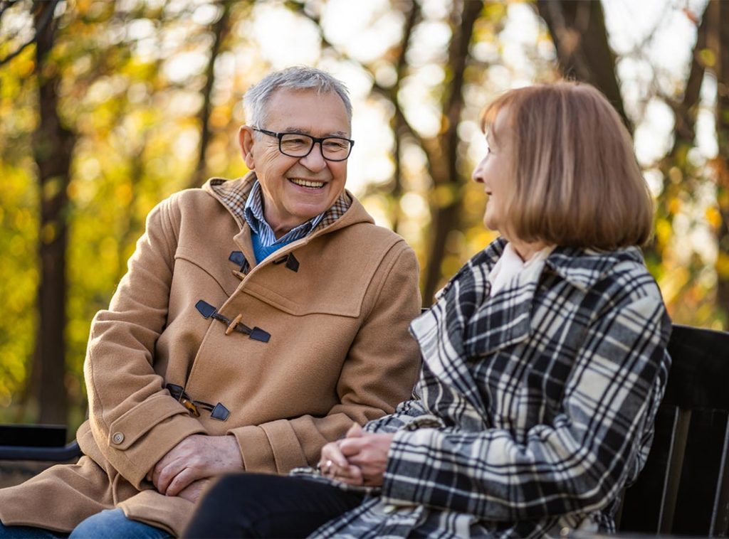 smiling senior couple sitting on park bench planning for retirement cedar rapids ia